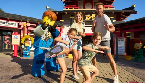 Family posing as Ninjas with Jay in front of LEGO Ninjago: The Ride