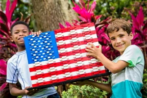 Two children posing with an American Flag made out of LEGO bricks