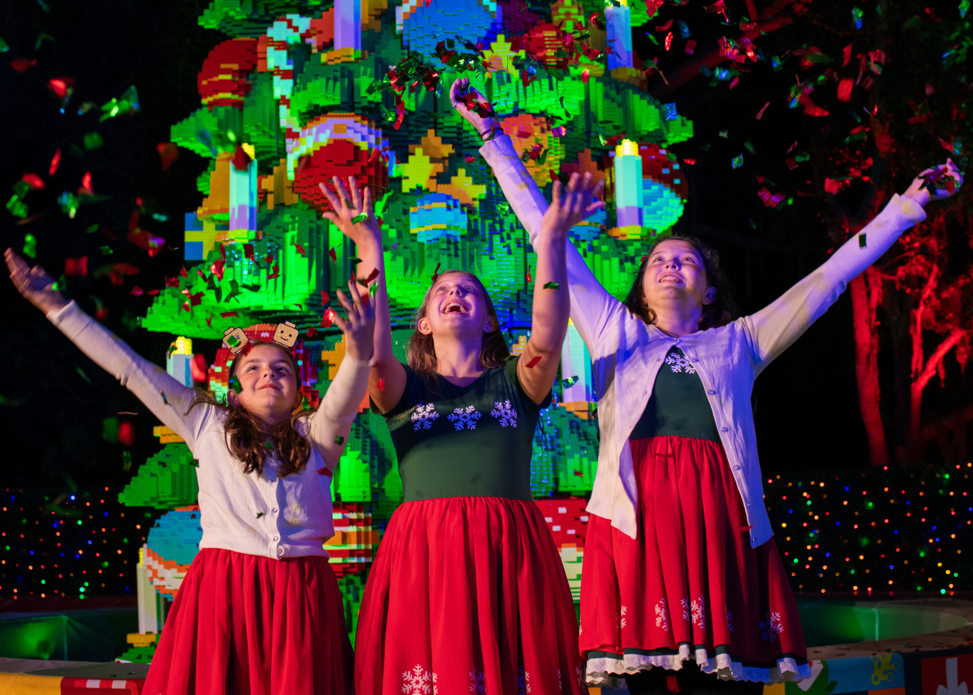 3 Girls in Christmas attire in front of LEGO Christmas Tree