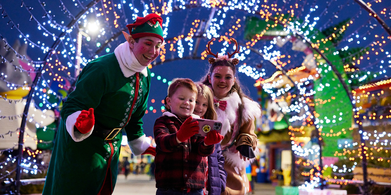 A child interacting with an elf during a holiday celebration at LEGOLAND Resort, surrounded by festive decorations and performers