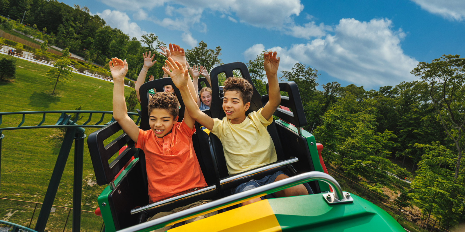 Kids lifting their hands up on roller-coaster 