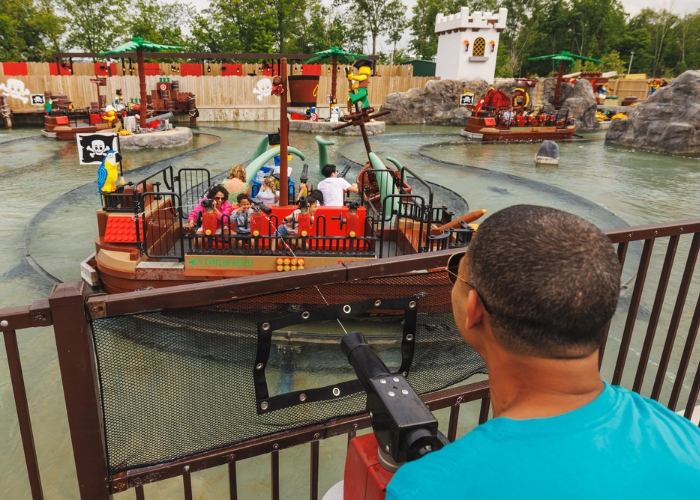 Guest aiming a water cannon at a pirate-themed boat ride at LEGOLAND Florida.